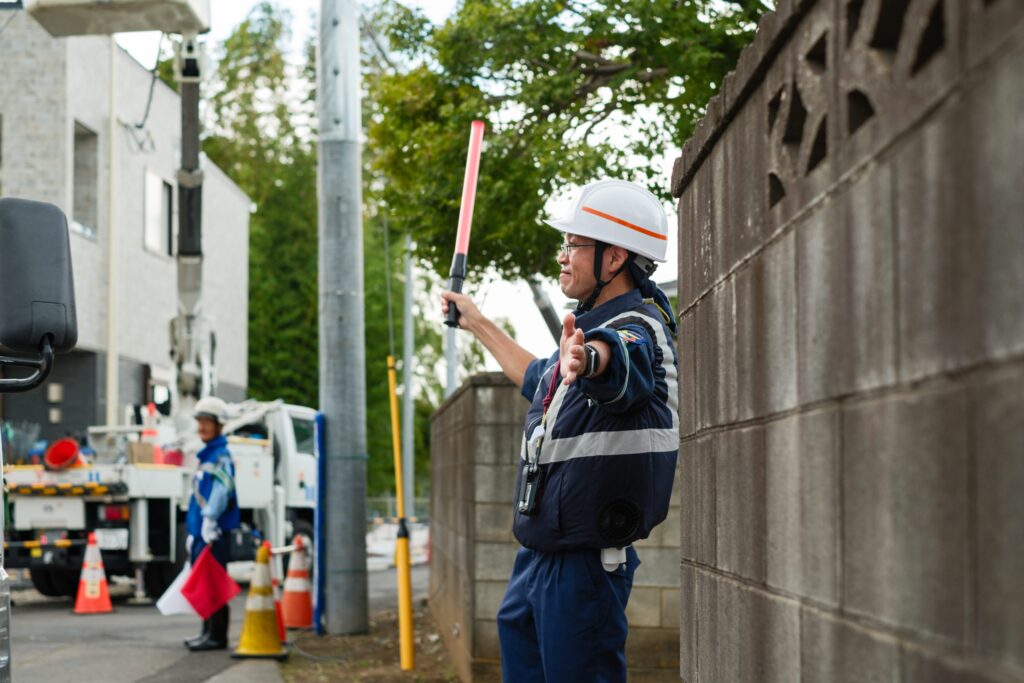 工事現場で歩行者の安全を確保するため交通誘導を行う警備員
